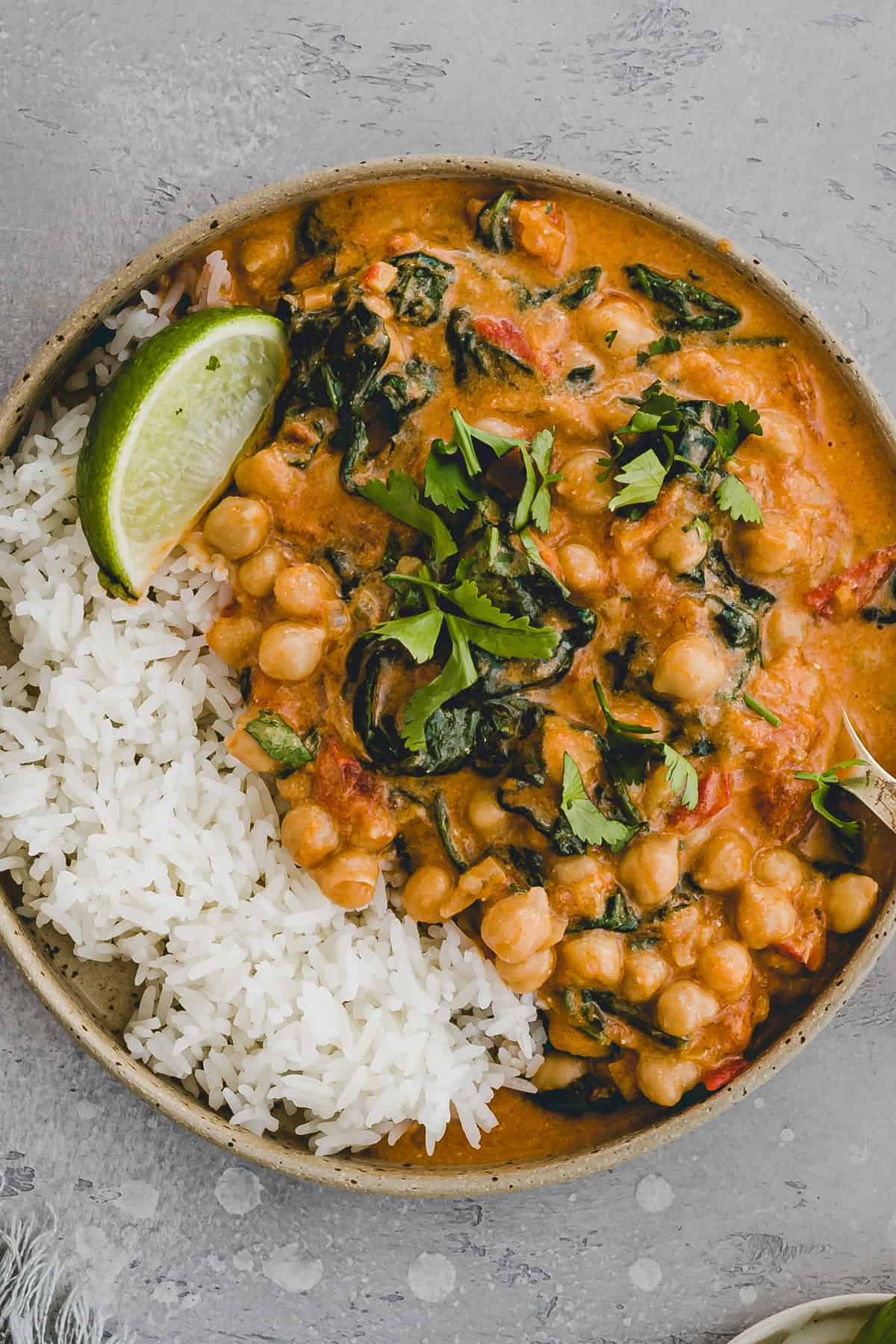 chickpea spinach curry with coconut milk and garnished with fresh cilantro and lime