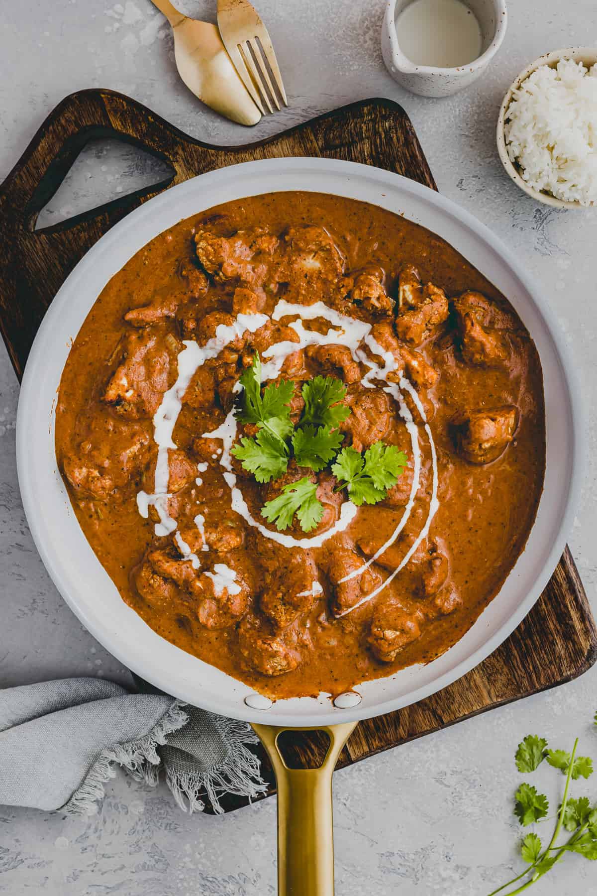 indisches blumenkohl curry in einer pfanne mit koriander dekoriert