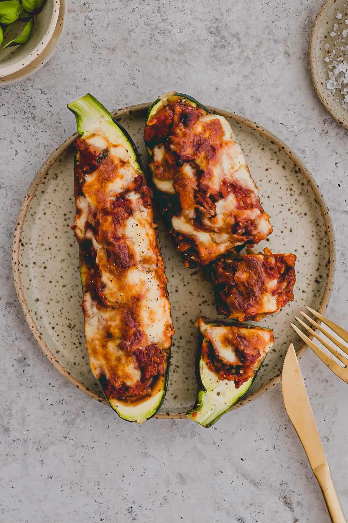 vegetarische zucchini schiffchen mit veganem hackfleisch und käse überbacken auf einem teller