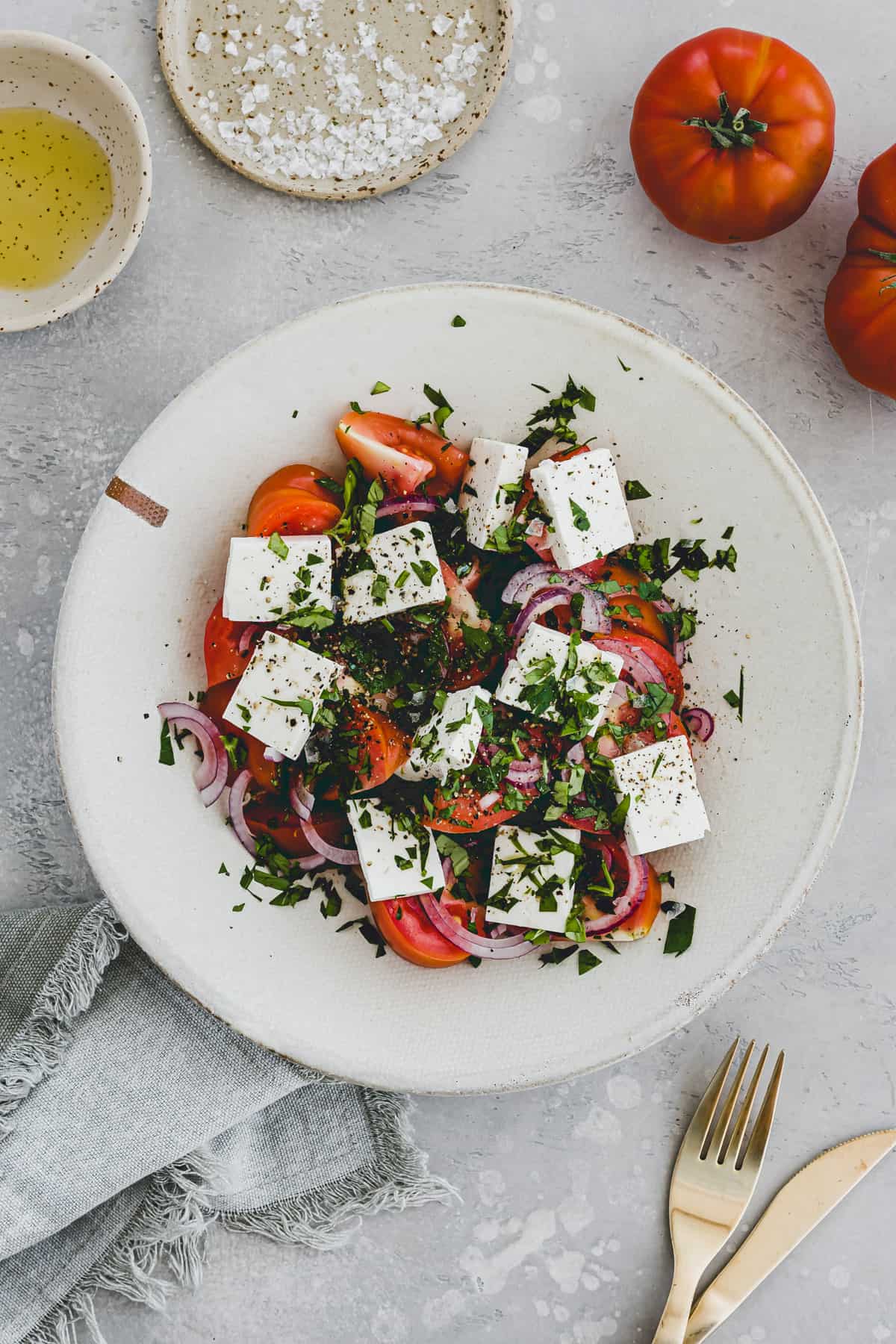 tomato salad with feta, onion, and fresh herbs served in a bowl