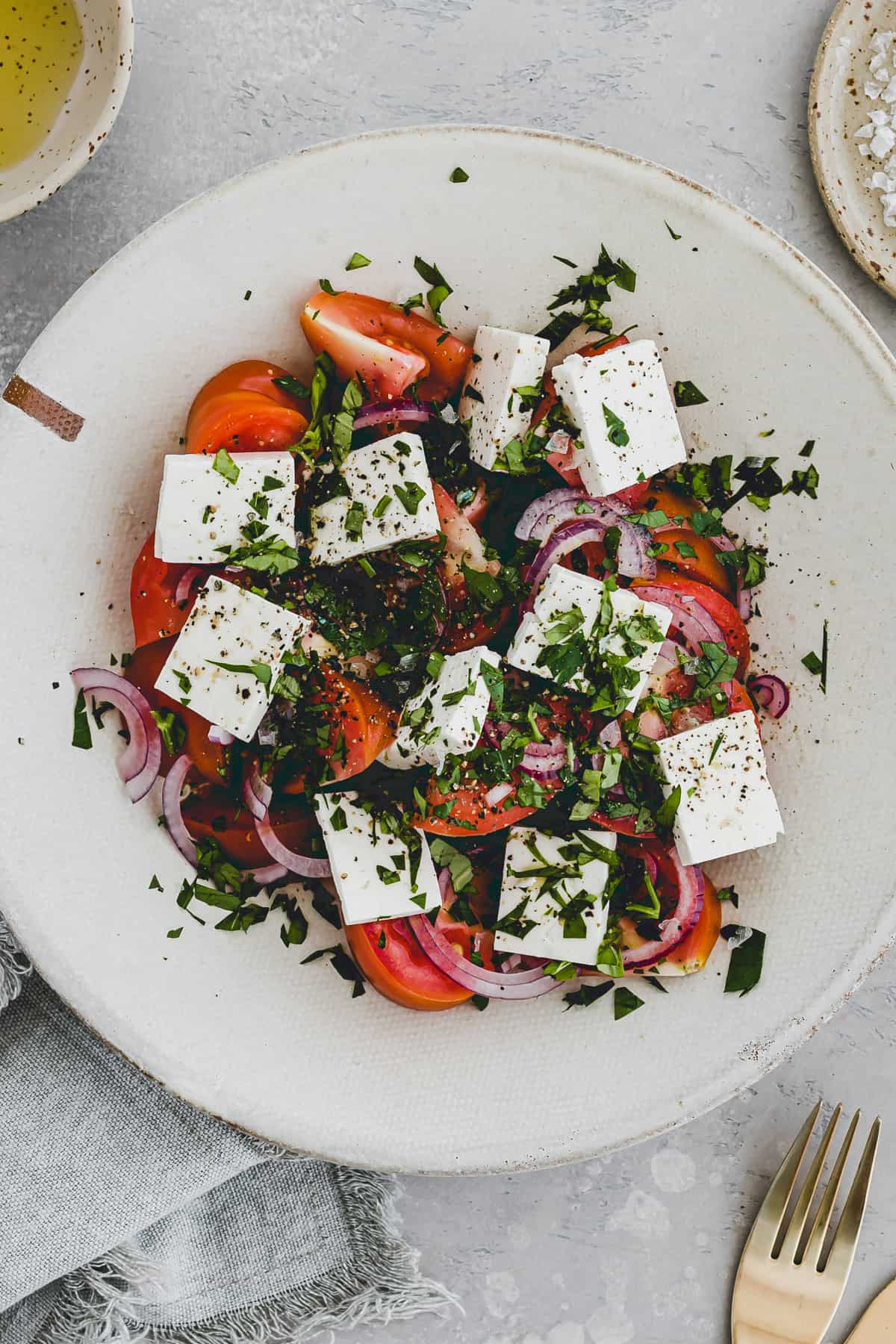 tomato feta salad in a bowl topped with fresh herbs
