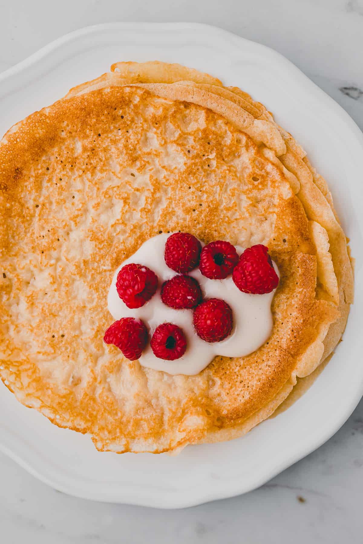 vegane crepes auf einem teller mit himbeeren