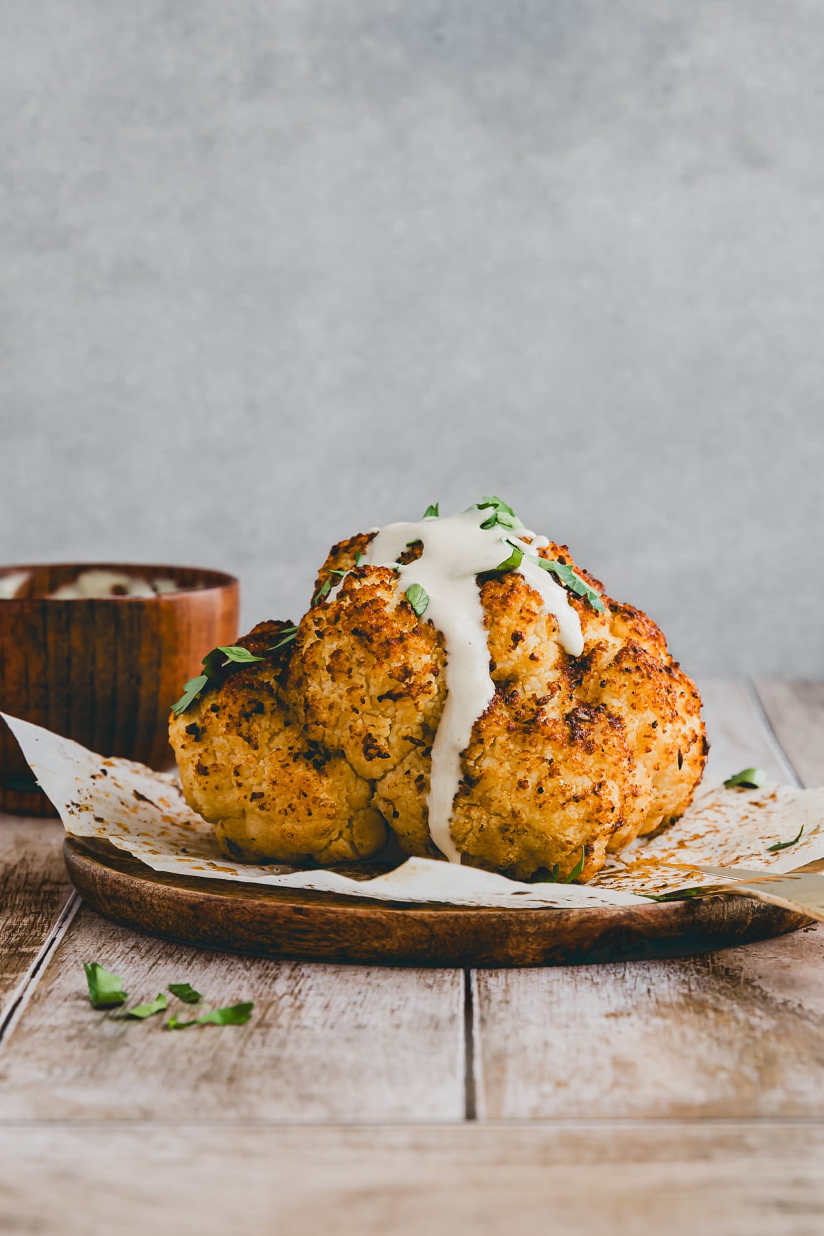 roasted cauliflower head drizzled with tahini sauce