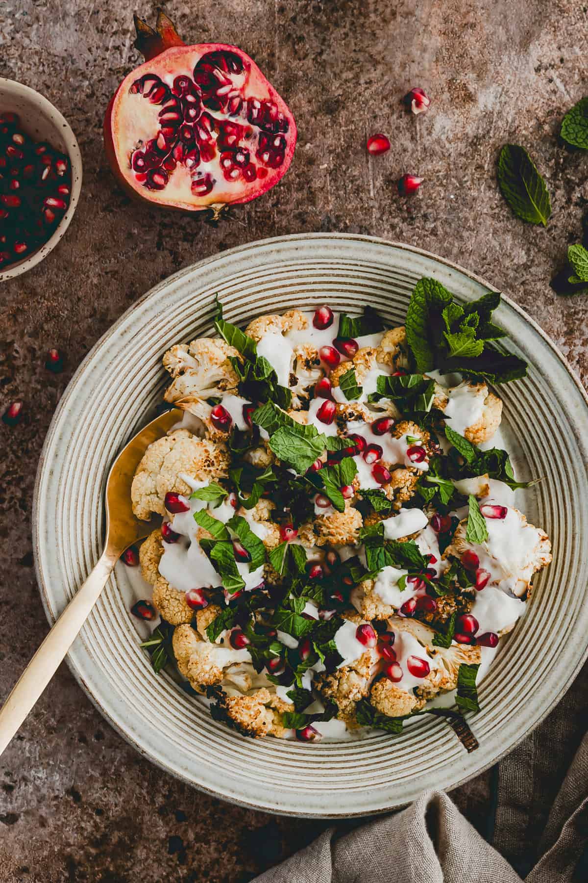 a plate with baked cauliflower florets topped with tahini and pomegranate seeds