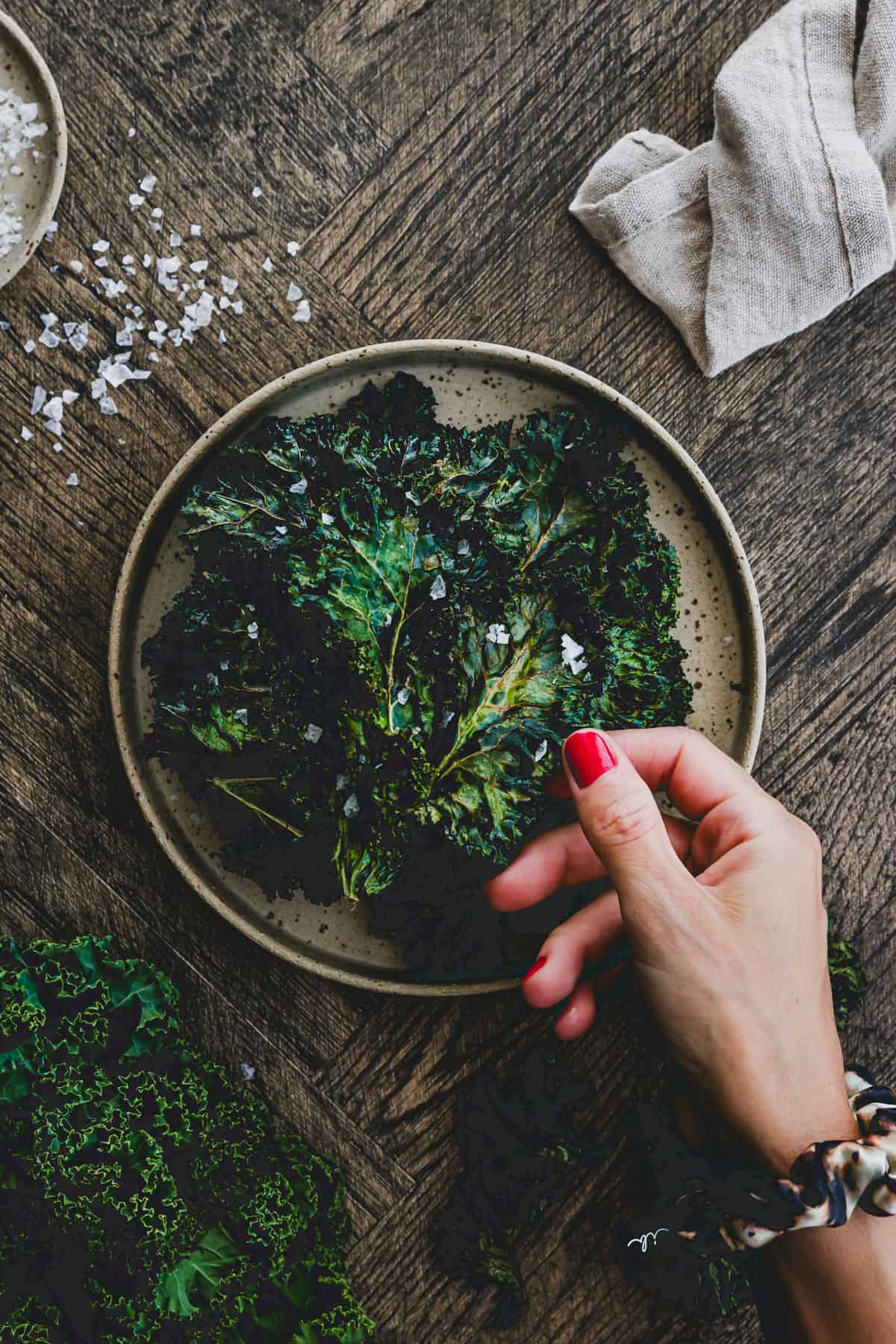 a hand taking one homemade kale chip