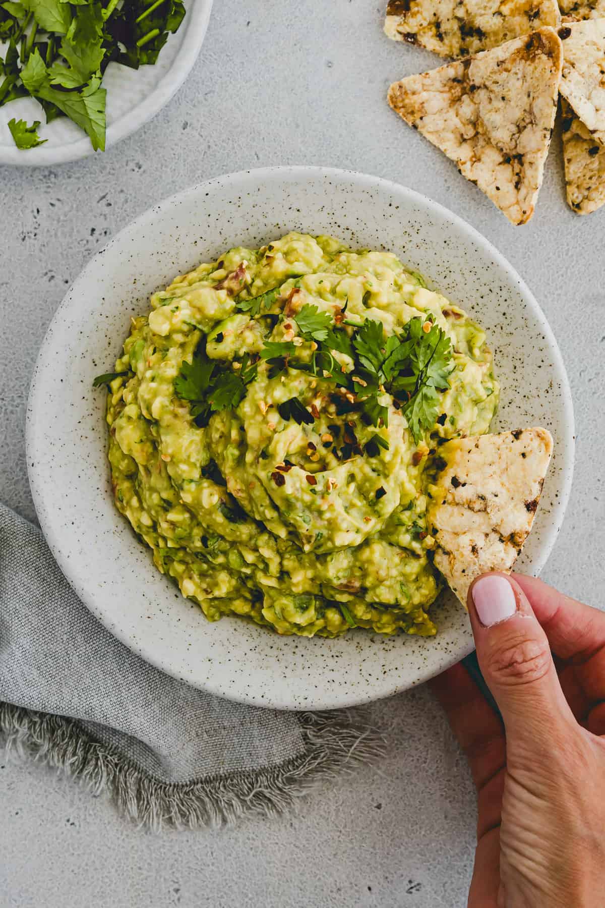 ein hand greift mit einem nacho in guacamole