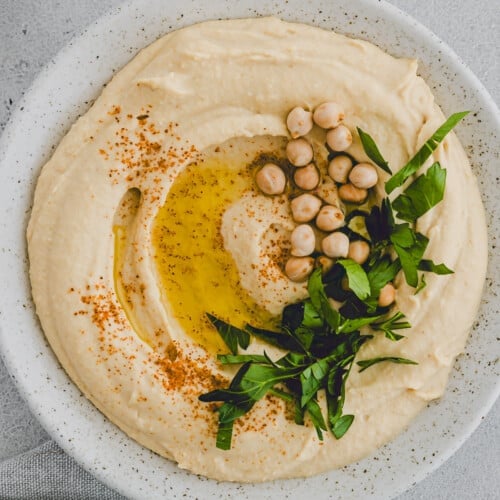 homemade hummus served in a bowl with olive oil and parsley