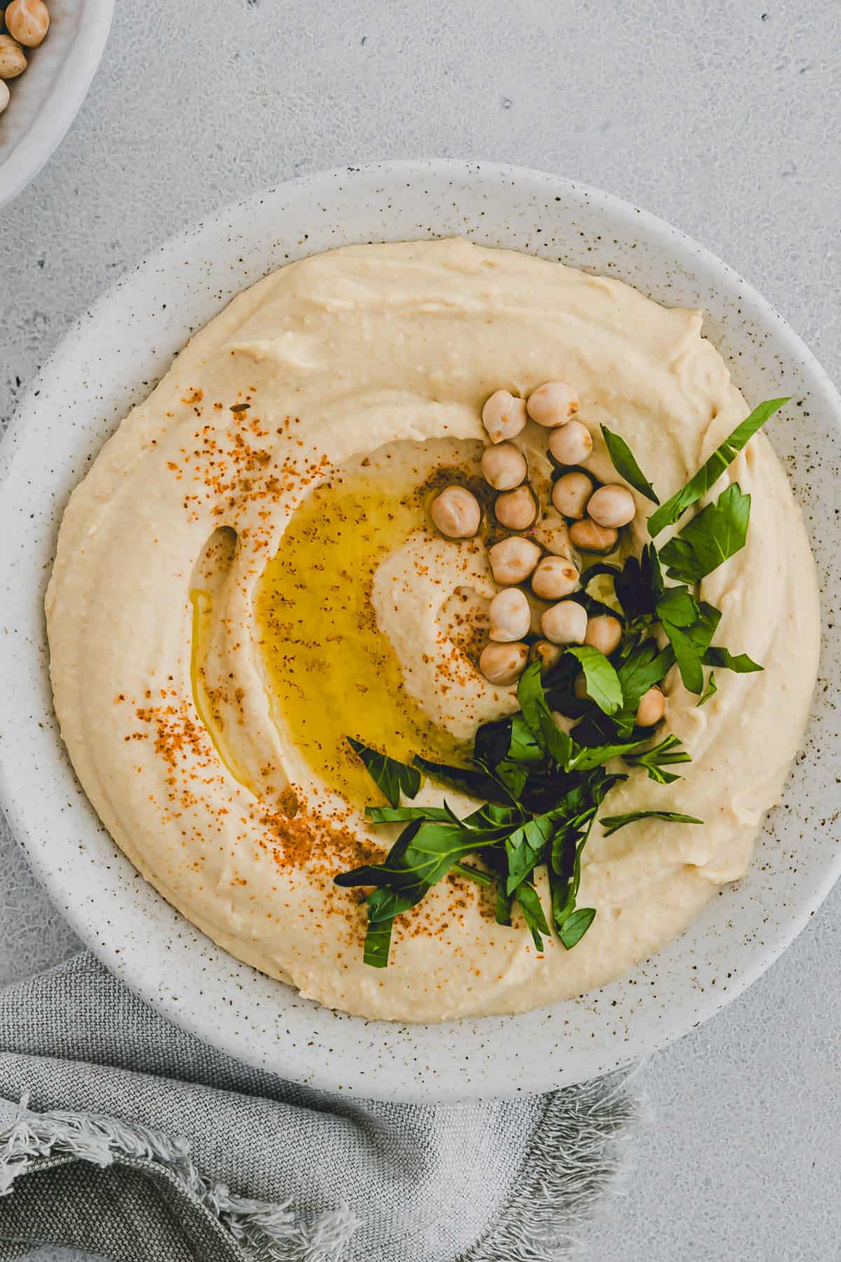 selbstgemachter hummus in einem teller mit petersilie und olivenöl dekoriert