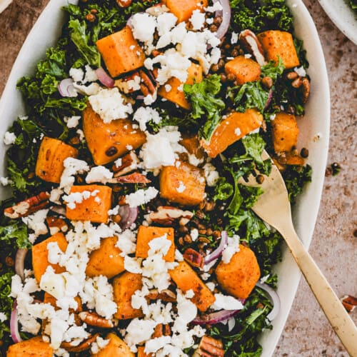 kürbissalat mit linsen, grünkohl, und feta auf einer platte serviert