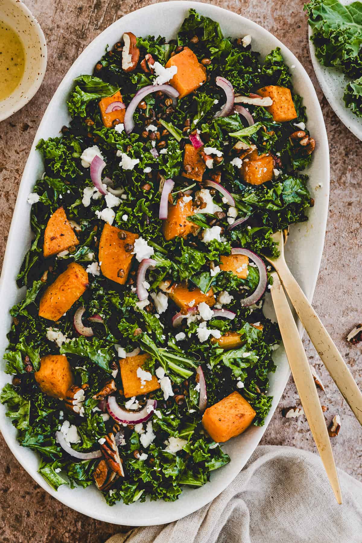 kürbissalat mit grünkohl auf einer platte mit goldigem besteck