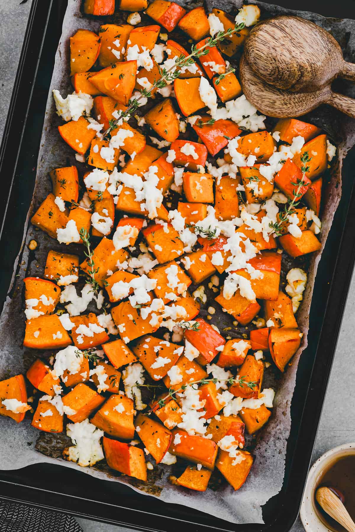 roasted butternut squash on a baking tray with melted feta cheese on top