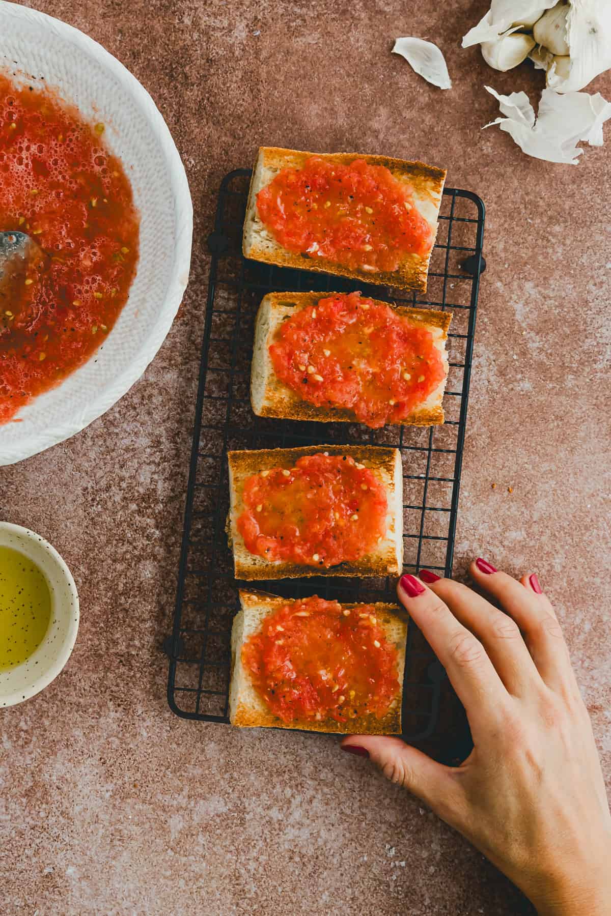 eine hand greift nach spanischem brot mit tomaten