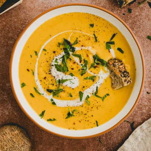 red lentil soup served in a bowl with fresh bread
