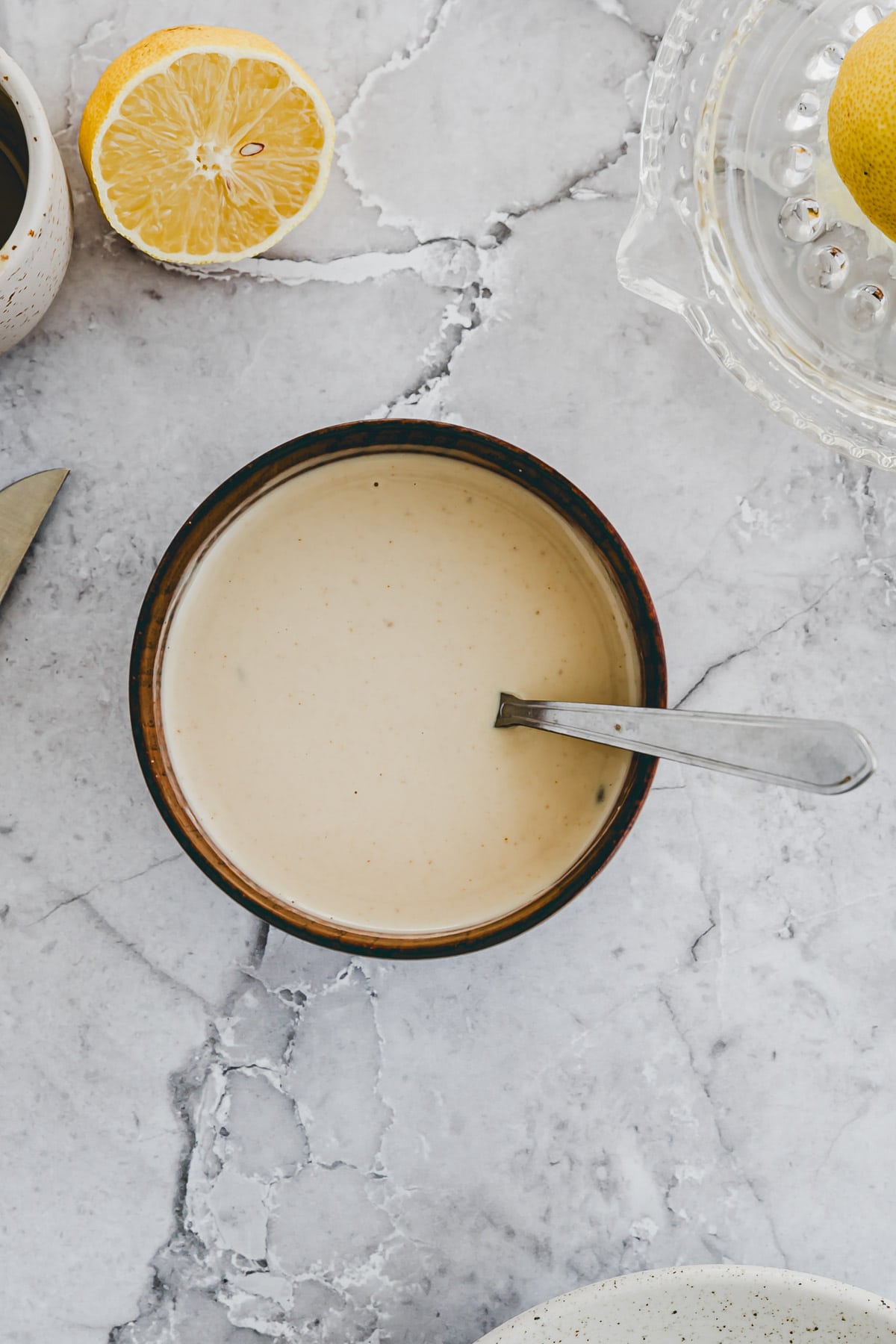 tahini dressing in a small wooden bowl next to a lemon