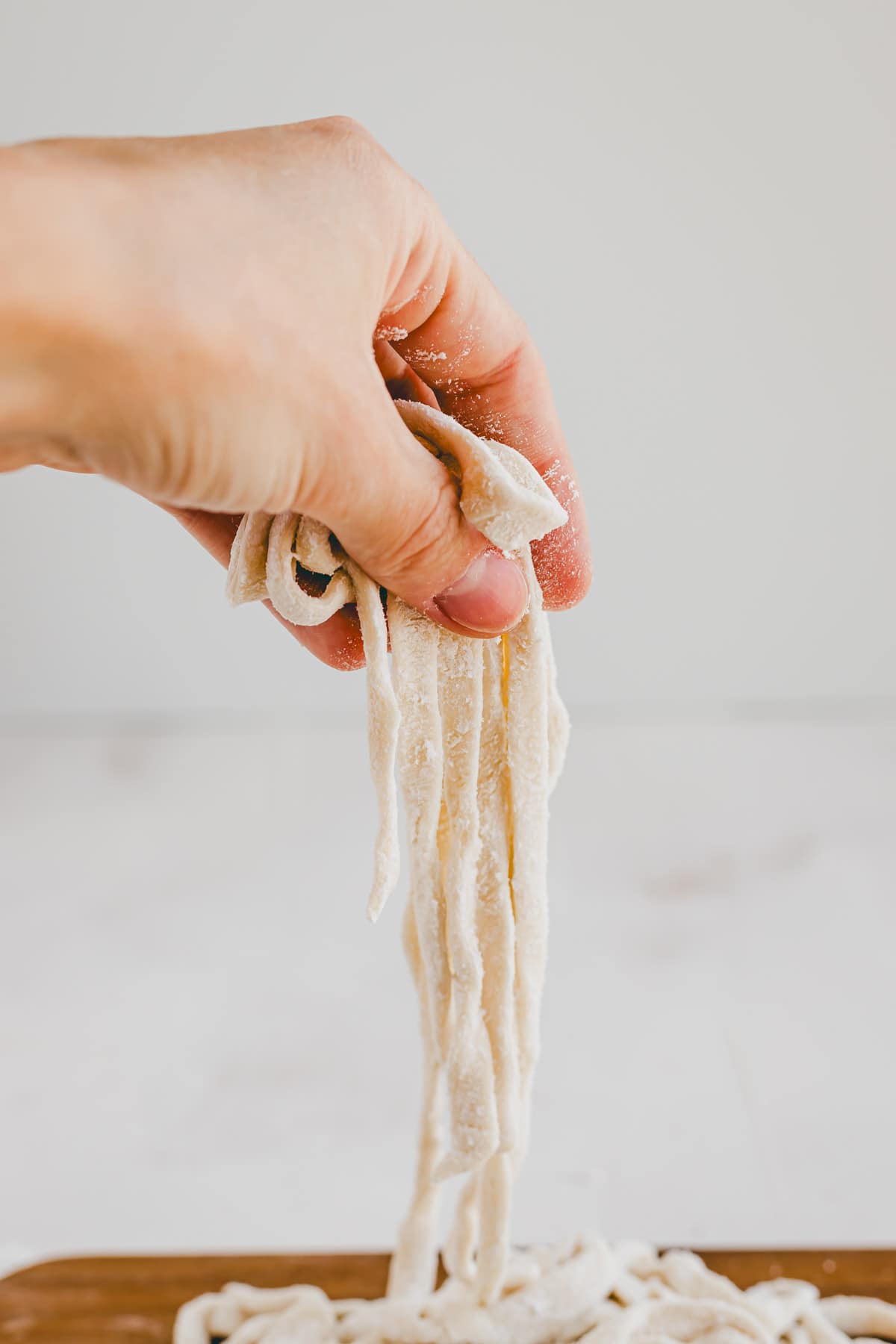 a hand holding fresh udon noodles