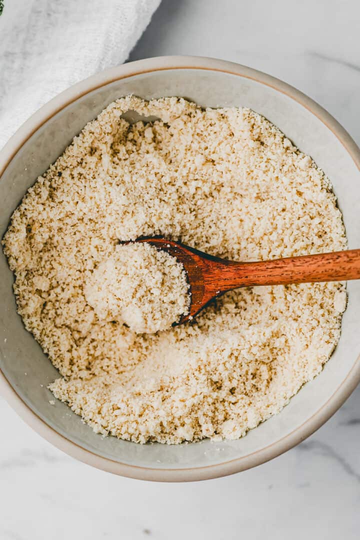 vegan parmesan cheese in a bowl with a wooden spoon