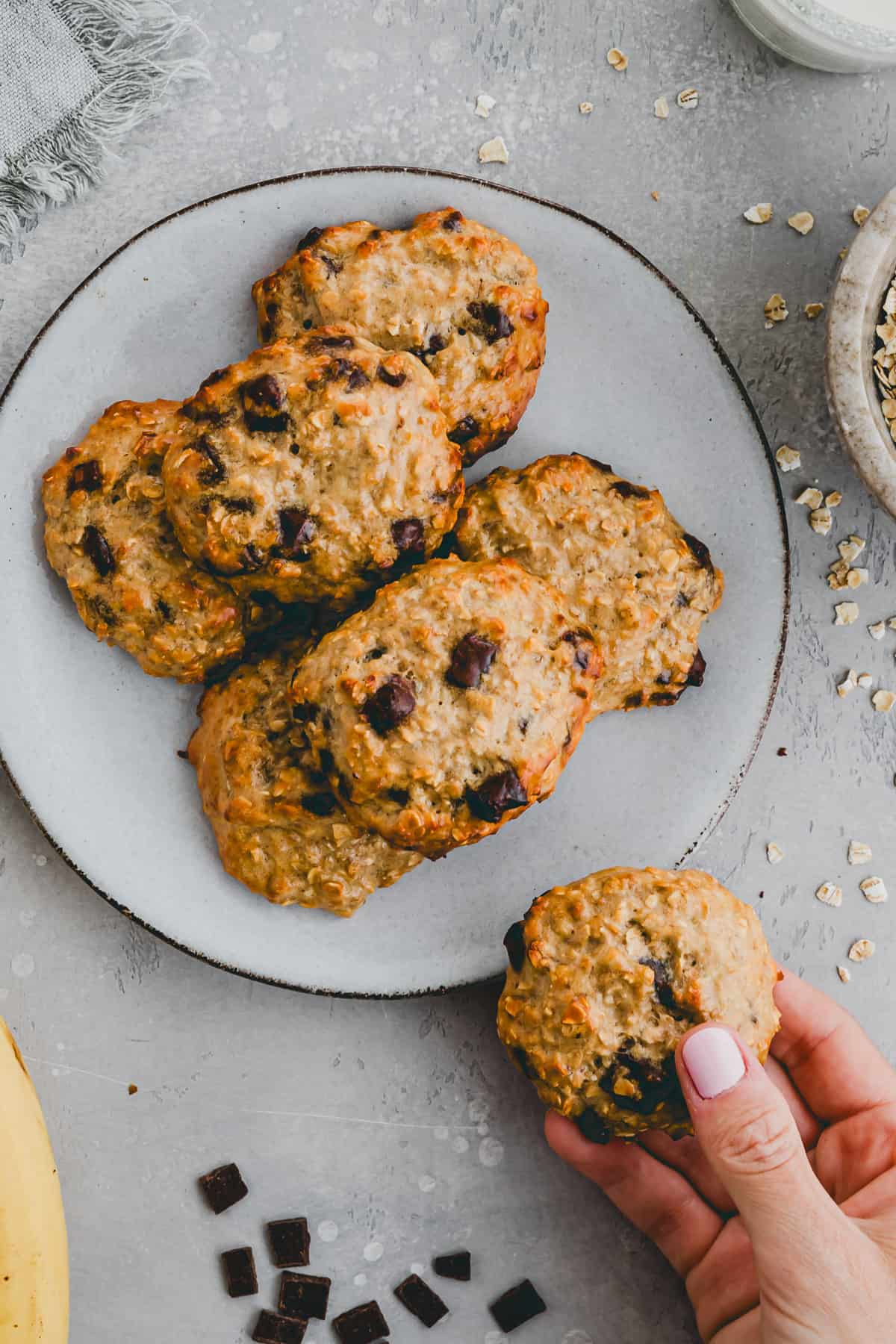 a hand holding a oatmeal protein cookie with chocolate chips