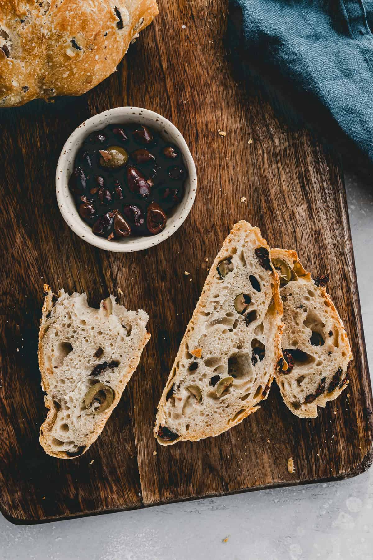 olivenbrot scheiben auf einem brett nebem einer schale oliven