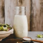 french dressing in einem glas neben einem salat