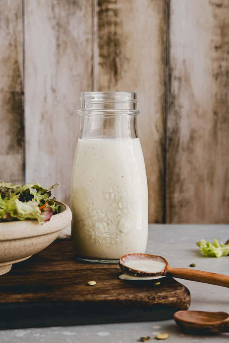 french dressing in einem glas neben einem salat