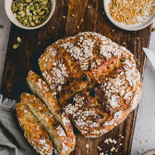 sliced no knead seeded oat bread on a cutting board