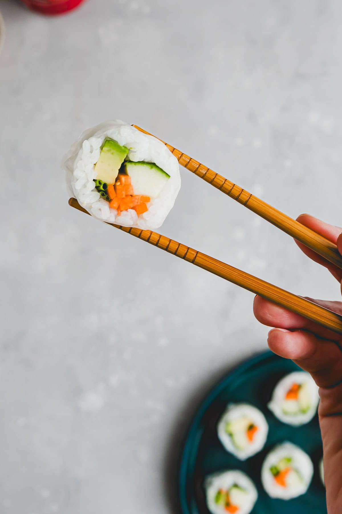 a chopstick holding a rice paper sushi maki roll