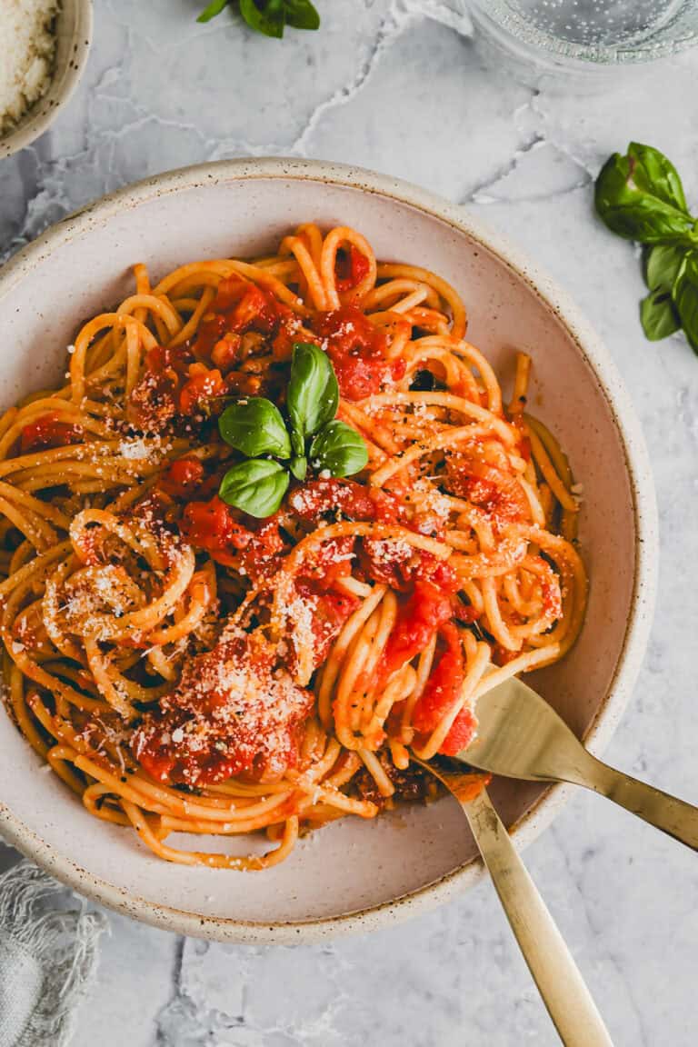 spaghetti pomodoro served in a bowl with parmesan cheese