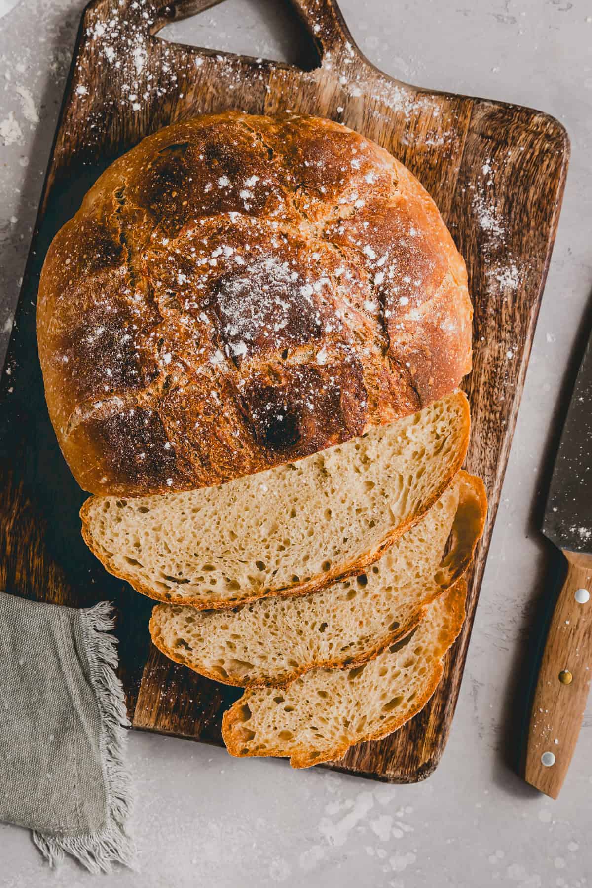 angeschnittenes bauernbrot auf einem holzbrett neben einem messer