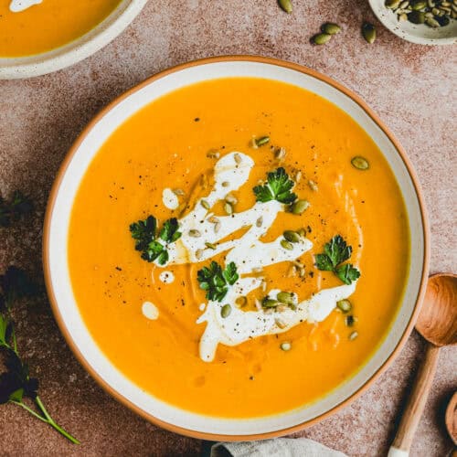 roasted pumpkin soup served in a bowl and topped with brown butter, yogurt, and fresh herbs
