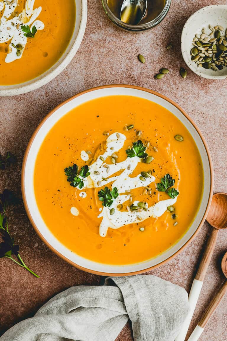roasted pumpkin soup served in a bowl and topped with brown butter, yogurt, and fresh herbs