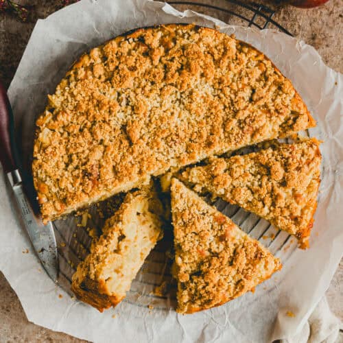 angeschnittener apfelkuchen mit streusel auf einem backpapier