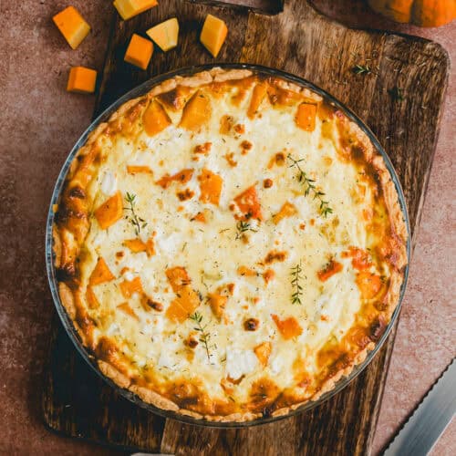 kürbis quiche mit feta in einer quiche form neben einem kürbis
