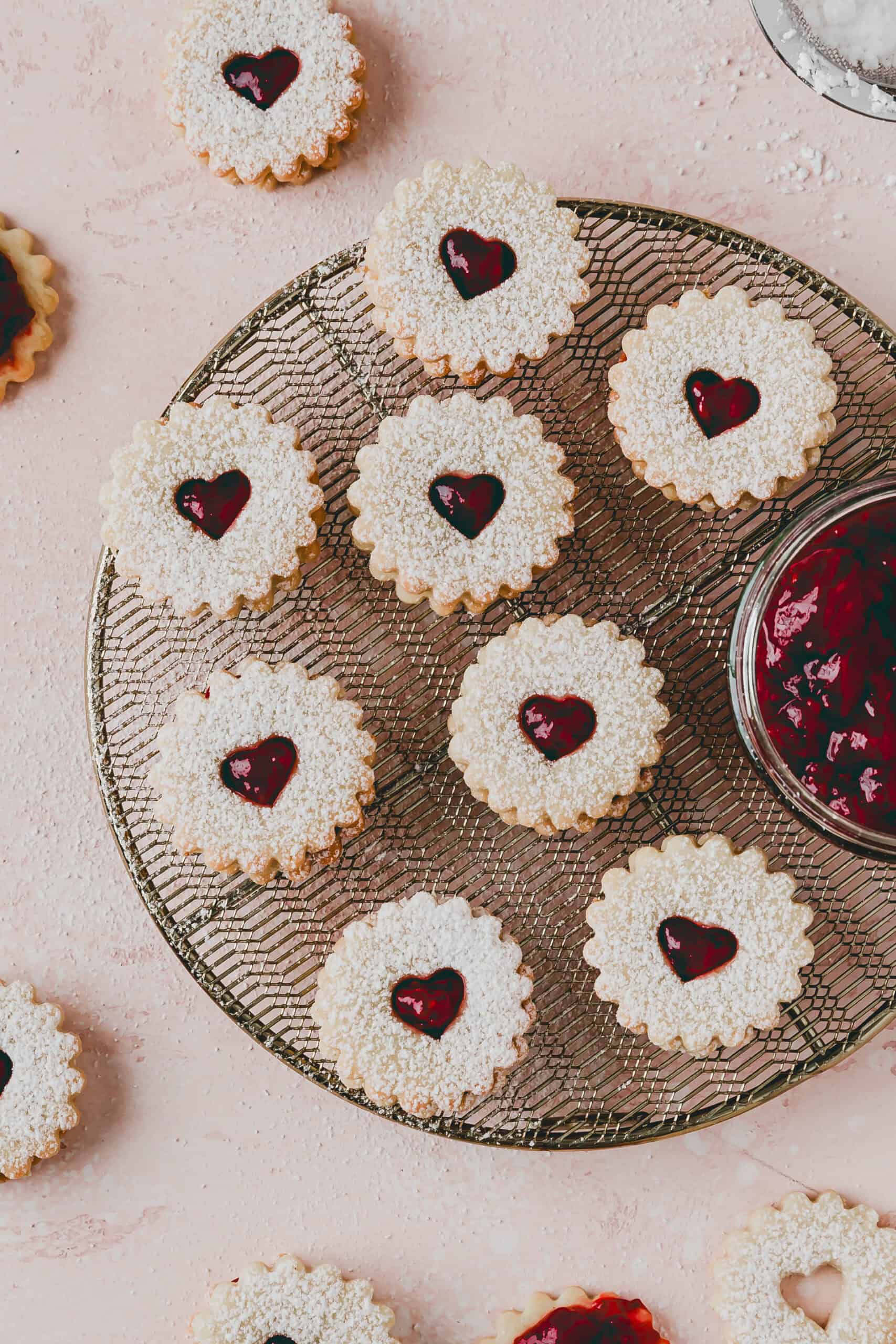 Linzer Cookies on a wire rack next to a jar of jam
