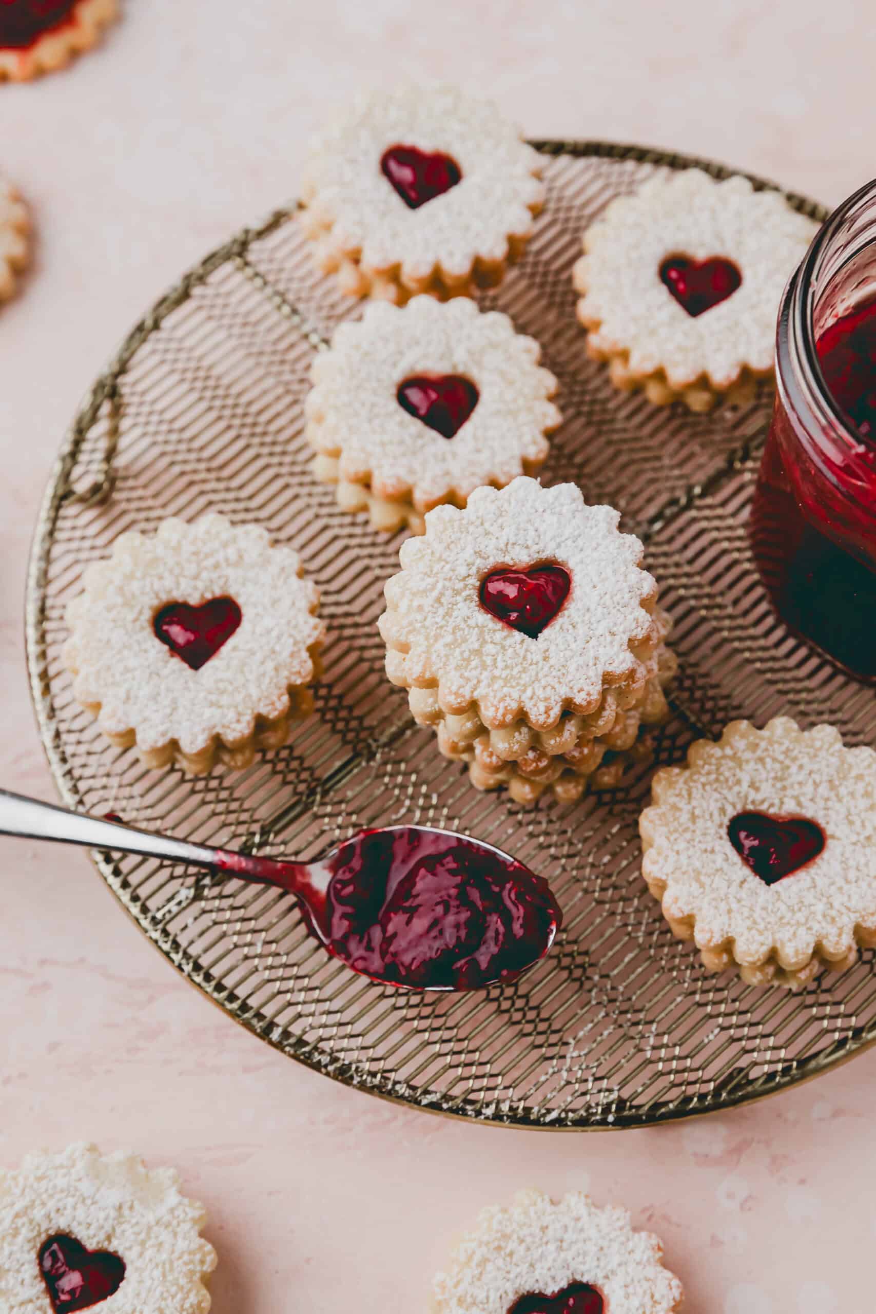 stabpled swiss spitzbuben cookies on a wire rack next to raspberry jam