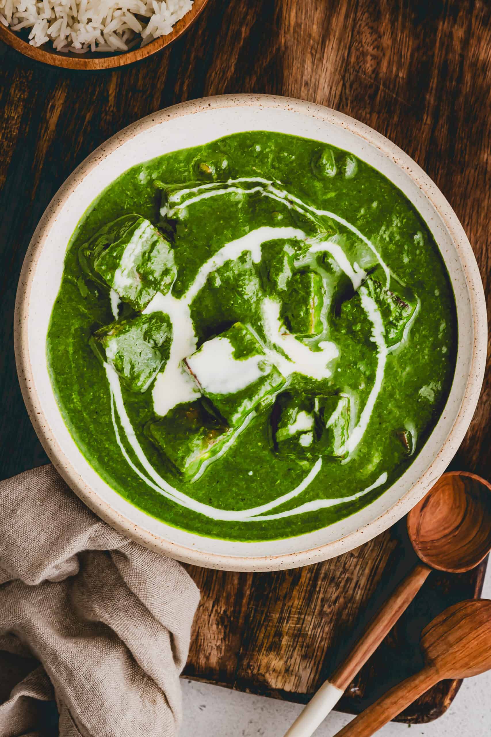 indian palak paneer served in a bowl topped with cream