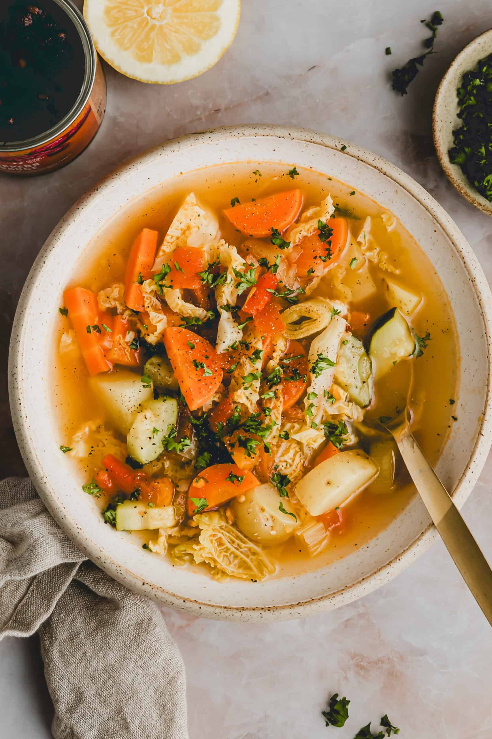 klassische Gemüsesuppe mit kartoffeln in einer schüssel mit einem goldenen esslöffel