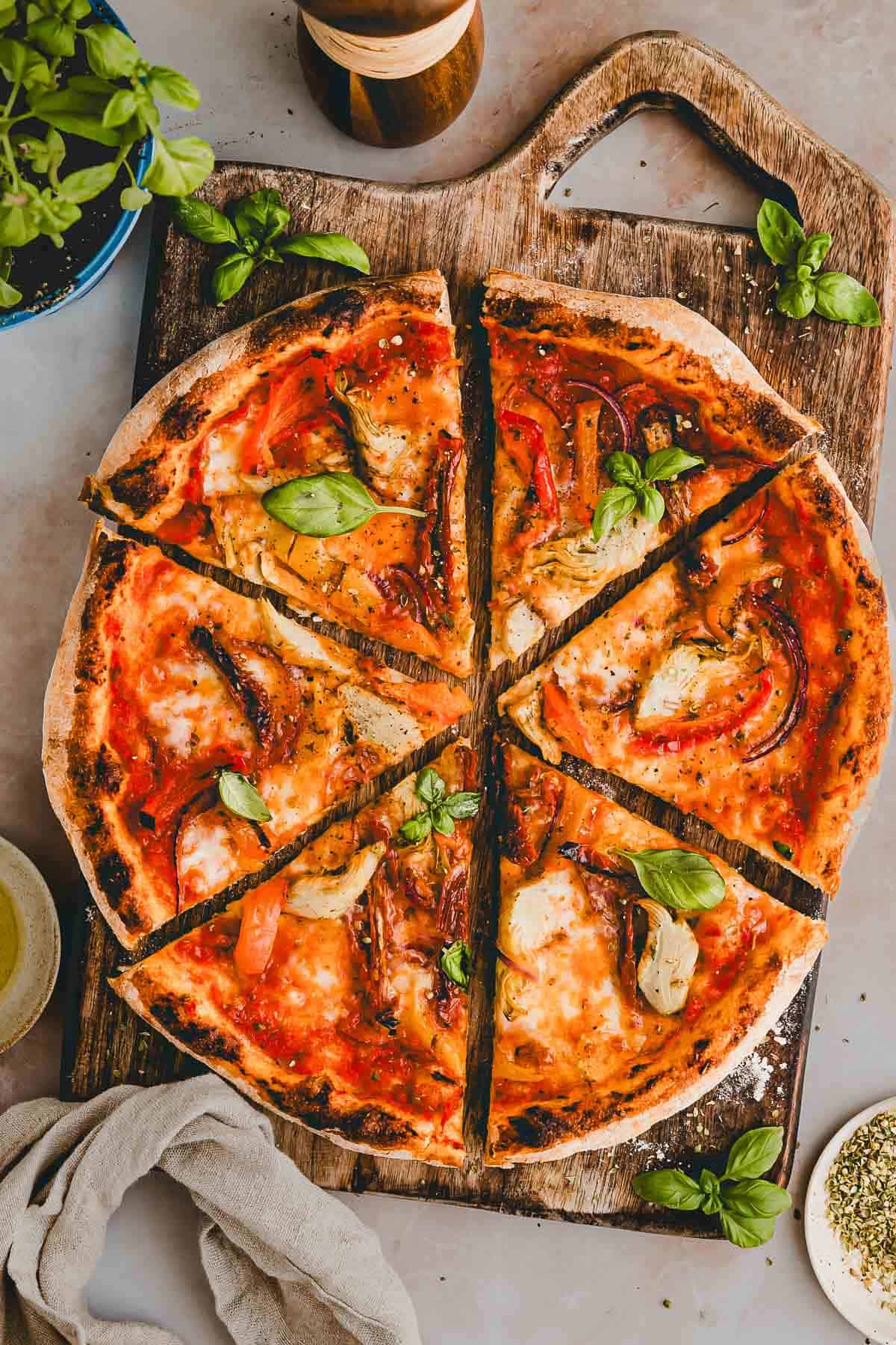 vegetarische pizza mit gemüse geschnitten und auf einem holzbrett serviert