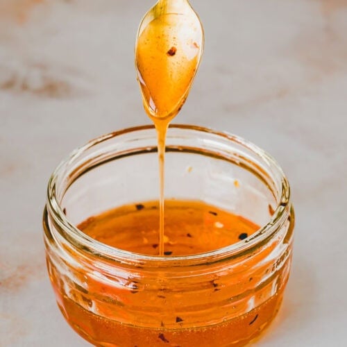 hot honey träuffelt über einen löffel in eine glasschale