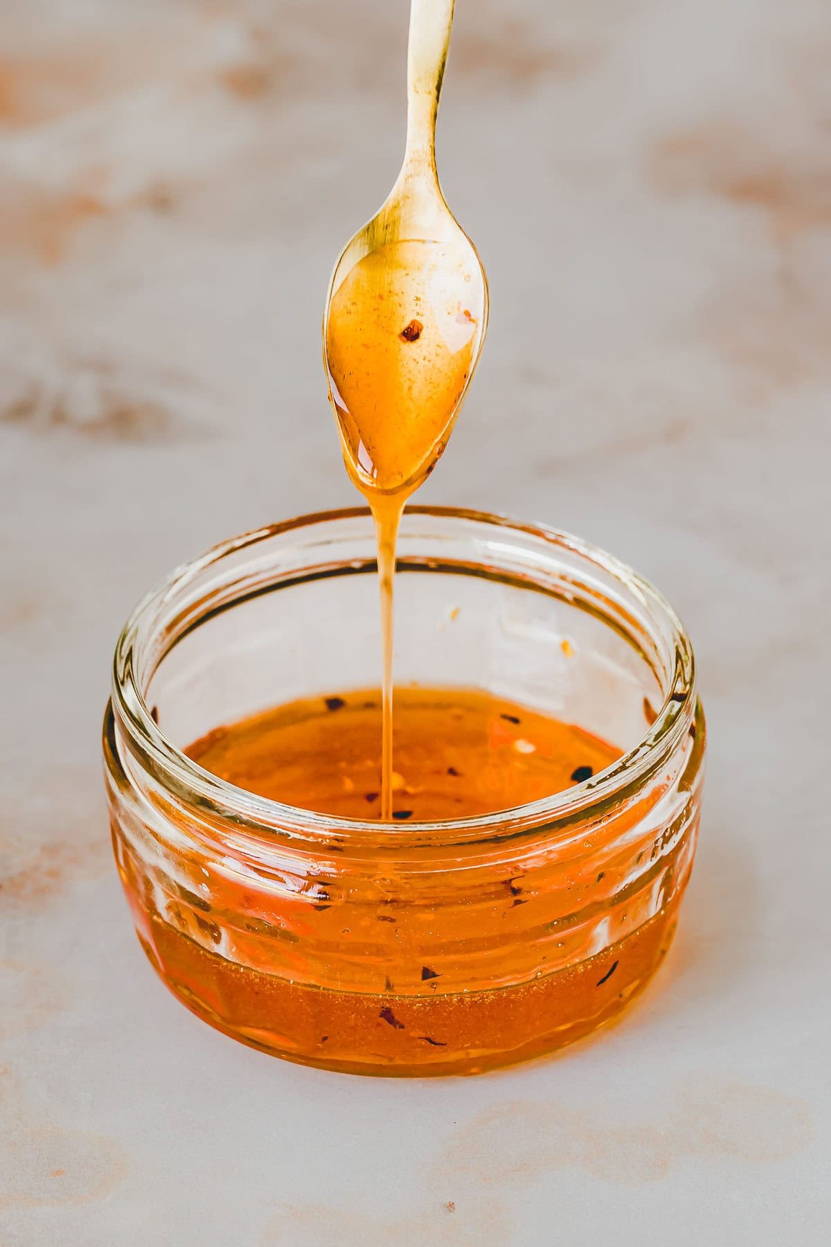 hot honey träuffelt über einen löffel in eine glasschale
