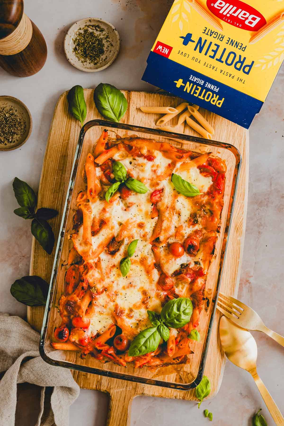 Penne Al Forno in einer Gratinform daneben eine Packung Barilla Protein+ Penne Rigate