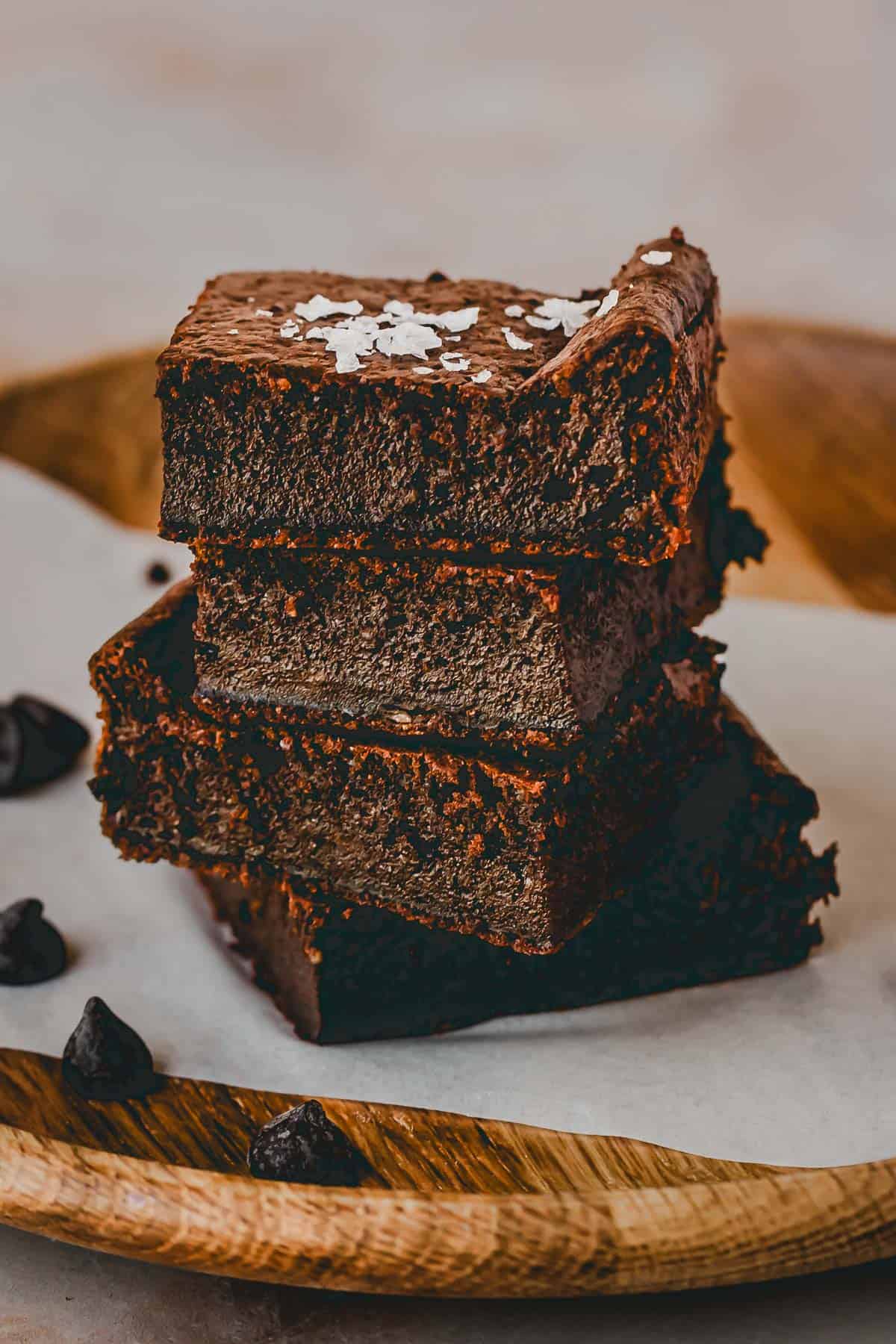 a staple of the baked cottage cheese brownies laying on a wooden plate with a piece of parchment paper