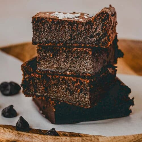a staple of the baked cottage cheese brownies laying on a wooden plate with a piece of parchment paper