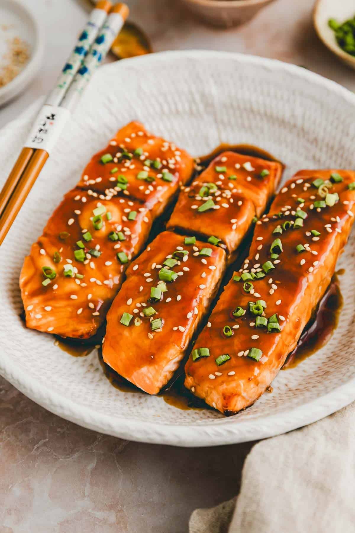 air fryer teriyaki salmon garnished with chopped scallions and sesame seeds served in a plate