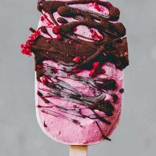 eine hand hält ein high protein eis am stiel mit schokolade überzogen