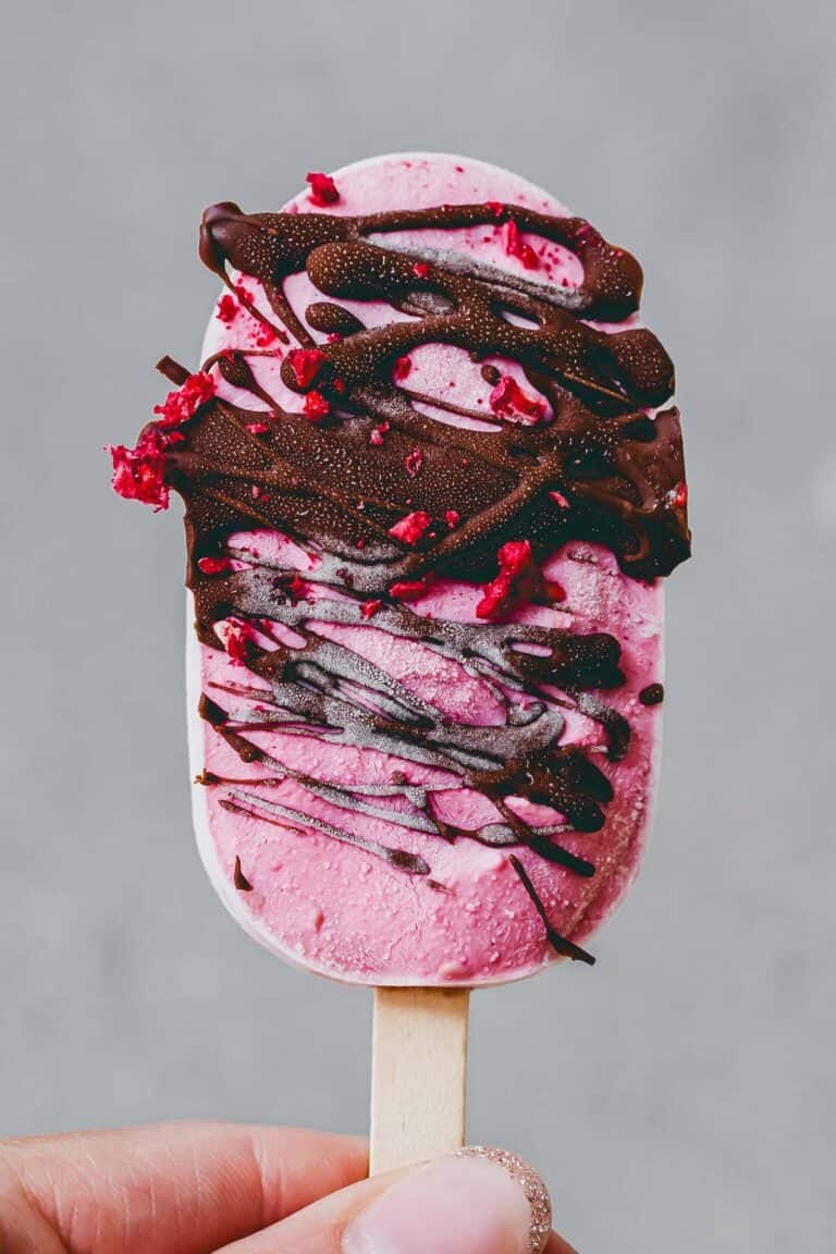 eine hand hält ein high protein eis am stiel mit schokolade überzogen