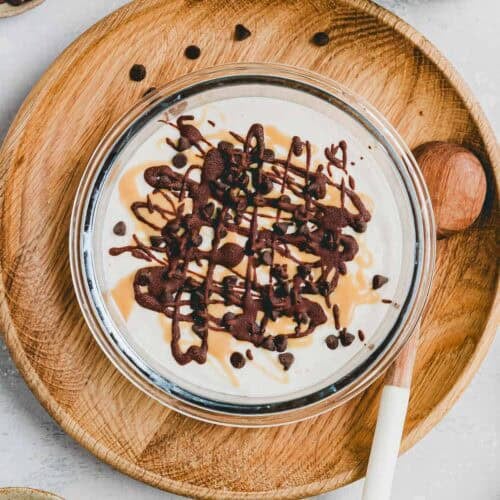 hüttenkäse eis mit banane in einer glas-tupperware mit topping aus schokolade und erdnussbutter