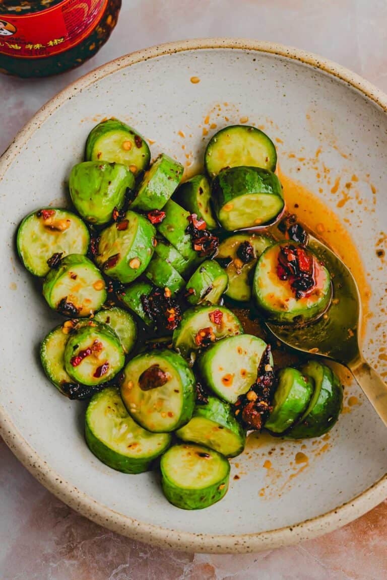 chinesischer gurkensalat in einer schüssel mit einem goldenen löffel