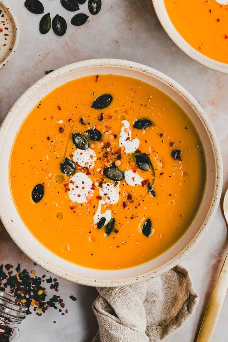 Pumpkin and Red Lentil Soup in a soup bowl garnished with yoghurt and pumpkin seeds