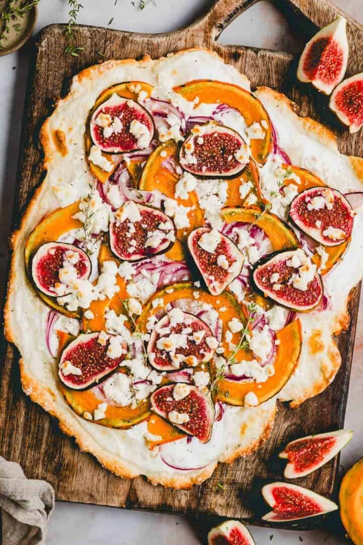 flammkuchen mit kürbis und feta auf einem holzbrett