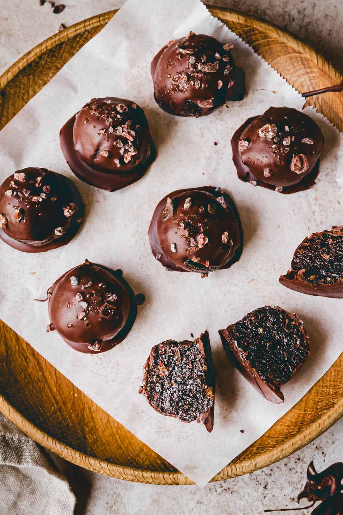 aufgeschnittene brownie protein balls auf einem mit backpapier belegten holzteller